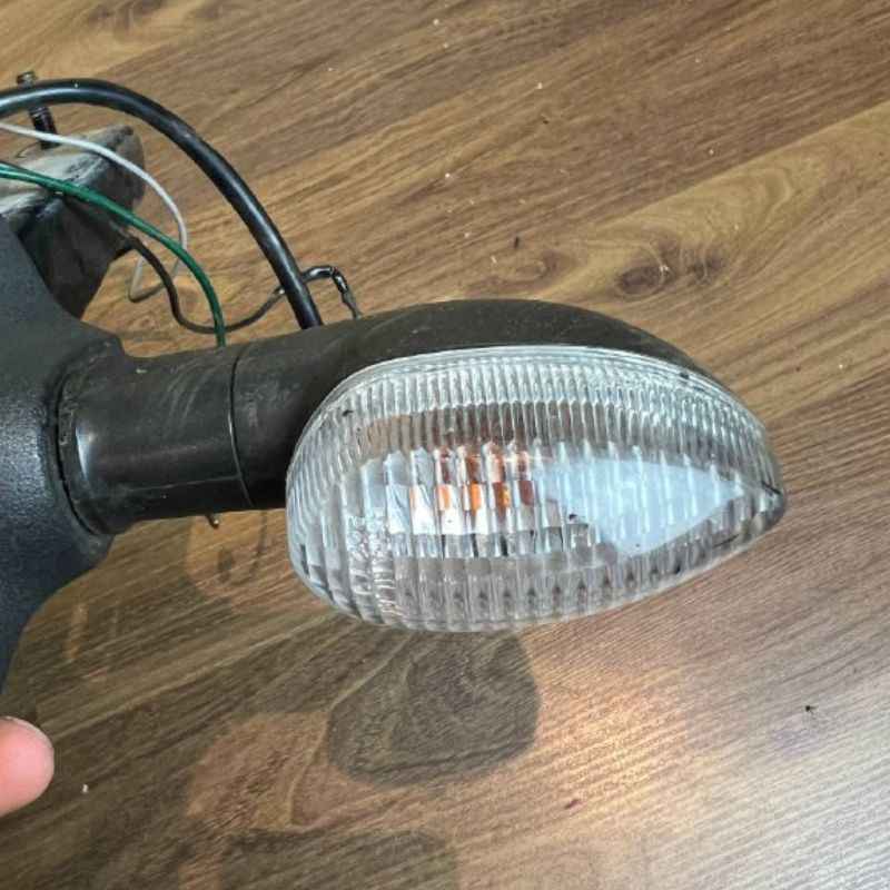 Close-up of the original Yamaha XSR155 OEM rear turn signal indicator mounted on the factory rear fender assembly. Genuine Yamaha indicator with clear lens and original wiring removed from the Neo Muscle project motorcycle.
