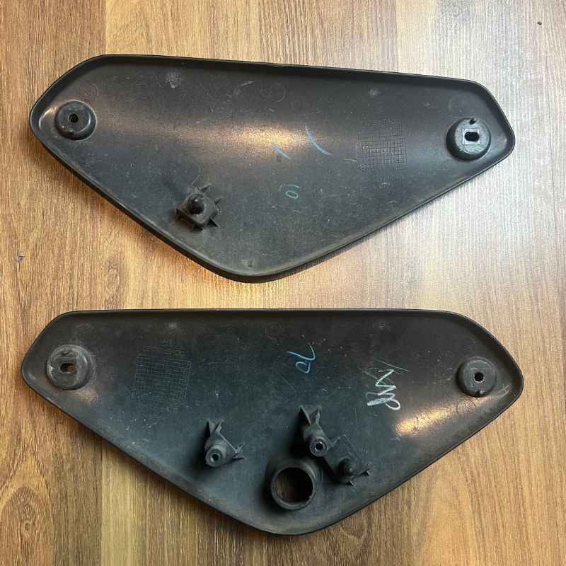 Back side of the original Yamaha XSR155 OEM side covers showing factory mounting tabs, clips and original attachment points. Genuine Yamaha left and right side panels removed from the Neo Muscle project motorcycle.