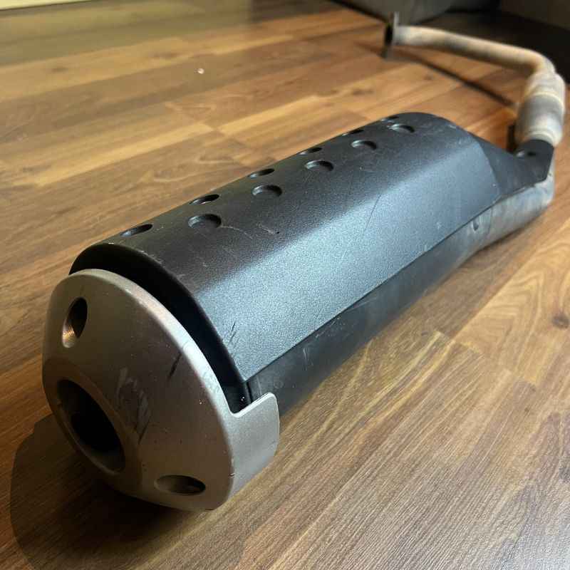 Angled side view of the original Yamaha XSR155 OEM exhaust muffler with factory heat shield and header pipe. Genuine Yamaha exhaust removed from the Neo Muscle project motorcycle in good used condition.