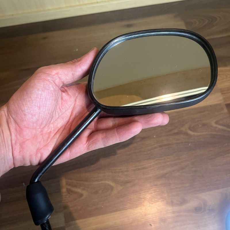 Close-up of an original Yamaha XSR155 OEM rear view mirror removed from the Neo Muscle project motorcycle. Genuine factory mirror in good used condition with original stem and mounting thread, ideal for replacement or restoration.
