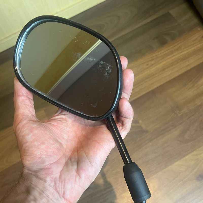 Close-up of the mirror glass on an original Yamaha XSR155 OEM rear view mirror removed from the Neo Muscle project motorcycle. Genuine factory Yamaha mirror showing the original reflective surface and housing in good used condition.