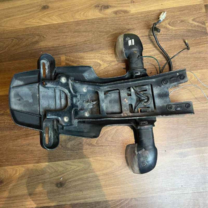 Angled view of the original Yamaha XSR155 OEM rear fender assembly with factory turn signals, wiring harness, license plate holder, reflector and mounting section. Genuine Yamaha rear fender removed from the Neo Muscle project motorcycle.