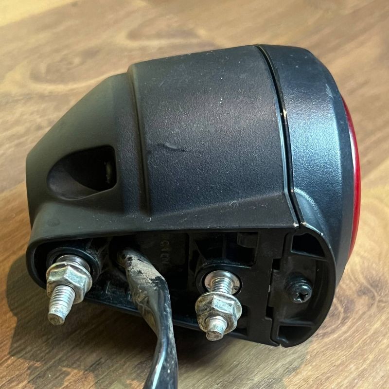 Close-up of the original Yamaha XSR155 OEM rear light showing the factory mounting studs, housing and wiring. Genuine Yamaha tail lamp, stop lamp and rear lamp assembly removed from the Neo Muscle project motorcycle for OEM replacement or restoration.