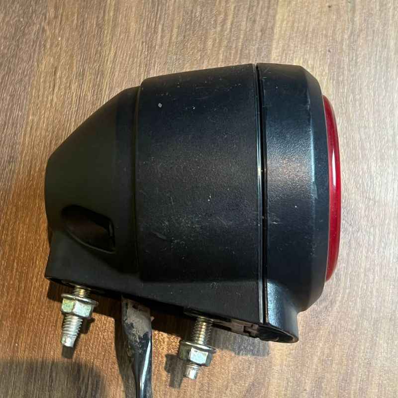 Right side view of the original Yamaha XSR155 OEM rear light housing with factory tail lamp, stop lamp and rear lamp assembly. Genuine Yamaha rear light removed from the Neo Muscle project motorcycle, showing the original mounting hardware and wiring.