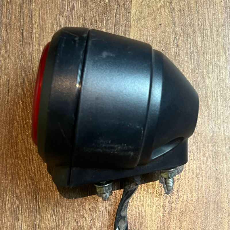 Side view of the original Yamaha XSR155 OEM rear light housing showing the factory tail lamp, stop lamp and rear lamp body with original mounting studs and wiring. Genuine Yamaha rear light removed from the Neo Muscle project motorcycle.
