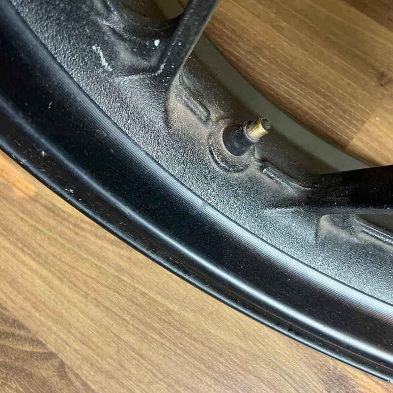 Close-up of the original Yamaha XSR155 OEM wheel rim and tire valve (velg) removed from the Neo Muscle project motorcycle. Genuine factory wheel detail.