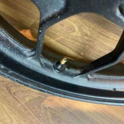Close-up of the original Yamaha XSR155 OEM wheel valve (velg) removed from the Neo Muscle project motorcycle. Genuine factory wheel detail.